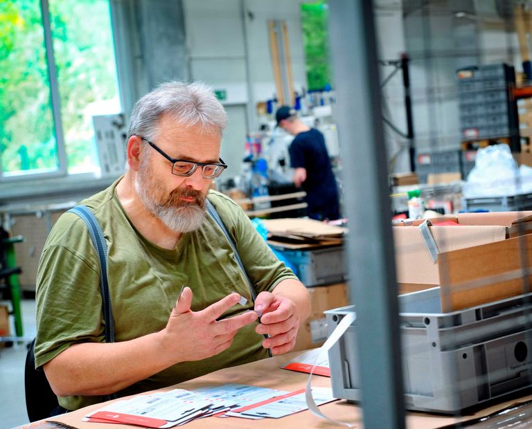 Wolfgang Starck sitzt an seinem Arbeitsplatz und klebt Etiketten