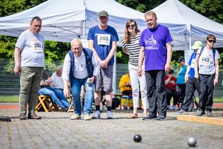 Sportlerinnen und Sportler treten beim Boule an