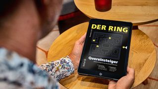 Eine Person sitzt mit einem Tablet mit der digitalen Ausgabe von DER RING am Tisch.