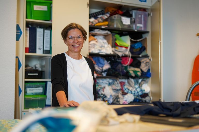 Anke Burre lächelt in die Kamera. Im Hintergrund sieht man ein Regal mit Stoffen.