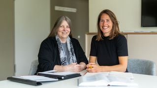 Silke Benter und Katrin Klaphake sitzten am Tisch und lächeln in die Kamera.