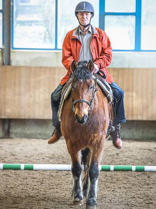 Ein älterer Mann reitet auf einem Pferd.