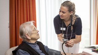 Eine junge Frau misst bei einer älteren Frau den Blutdruck