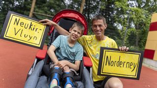 Vater und Sohn halten Schilder vom Start- und Zielort in der Hand