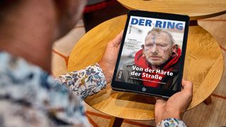 Ein Mann sitzt am Tisch und liest den digitalen RING auf dem Tablet.