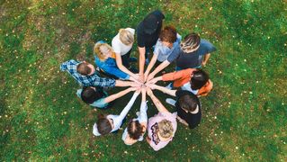 Eine gruppe von Menschen legen ihre Hände zu einen Team Huddle zusammen.