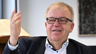 Pastor Pohl spricht mit erhobener Hand.