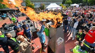 Das Olympische Feuer wird vor Publikum auf dem Sportplatz entzündet