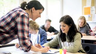 Ein Lehrerin erklärt einer Schülerin eine Aufgabe. 